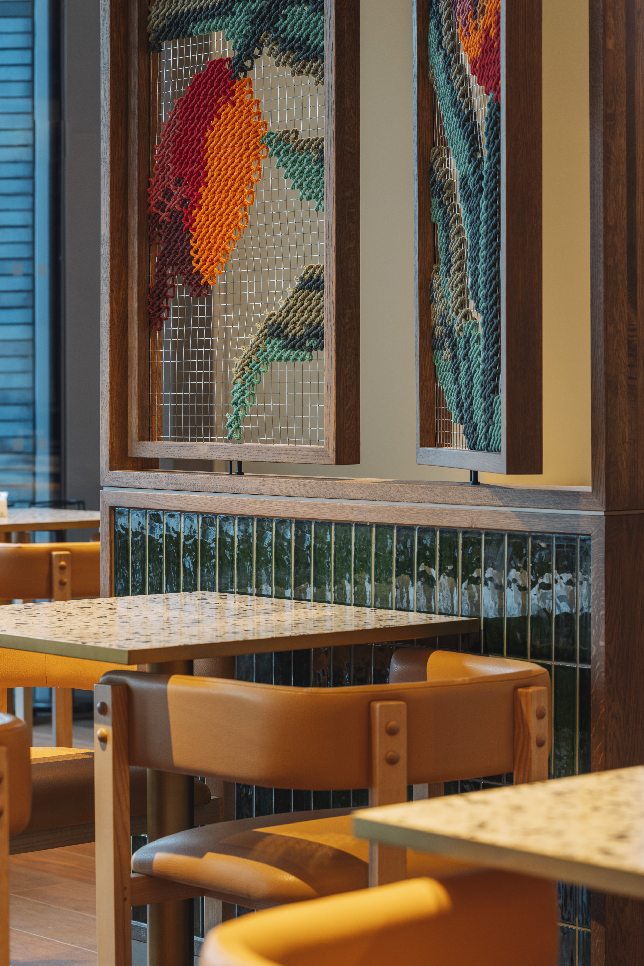 Yellow chairs beneath a woven tulip divider in the restaurant.