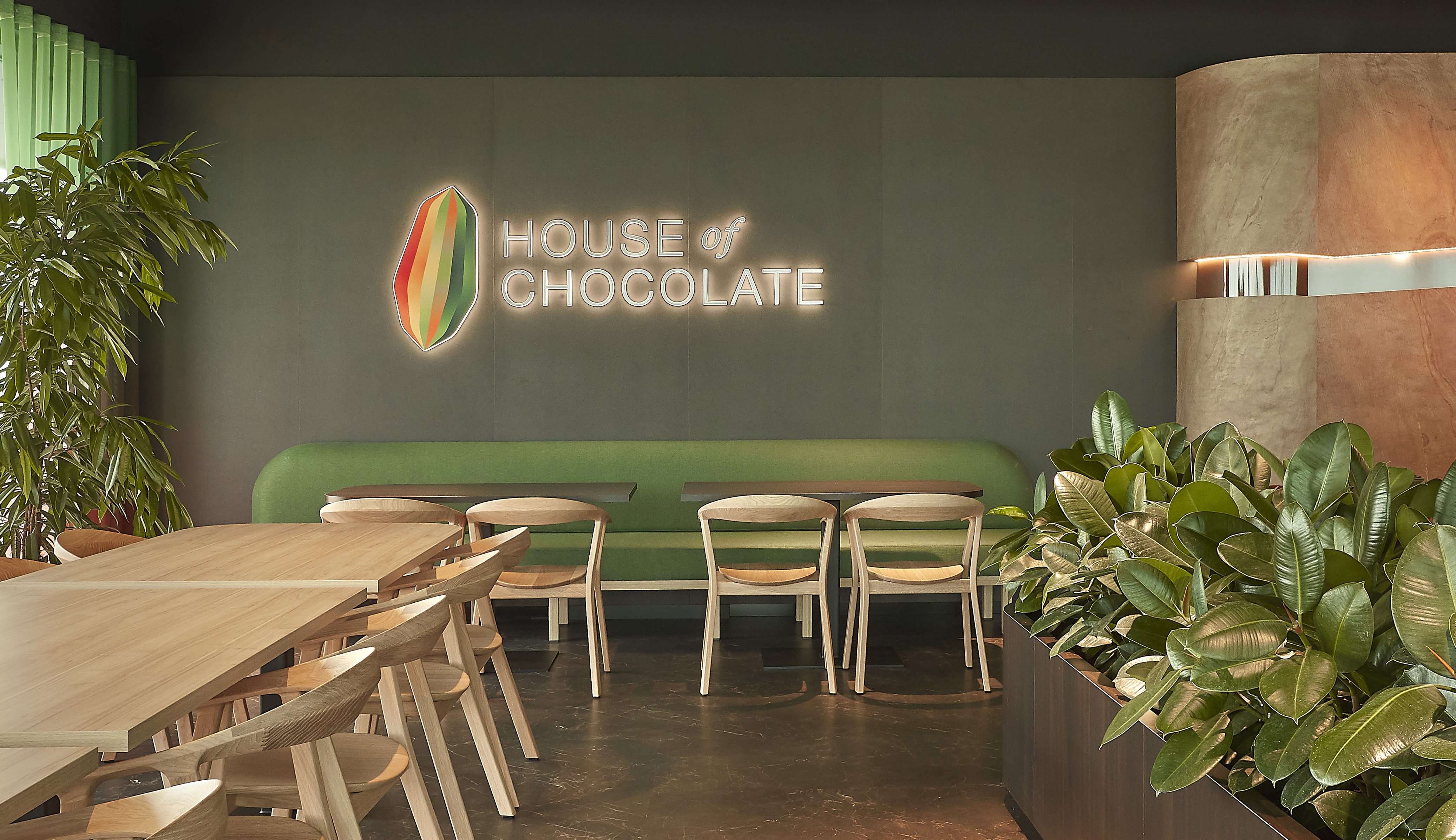 The seating area for House of Chocolate that includes green booths and natural woods.